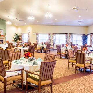 A spacious dining area with neatly arranged tables and chairs, well-lit by ceiling lights.