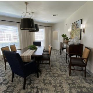 A modern dining room with a large table, chairs, and stylish lighting.
