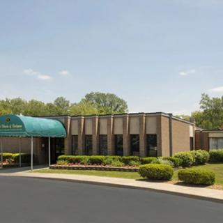 A modern building with a green canopy entrance and well-maintained landscaping.