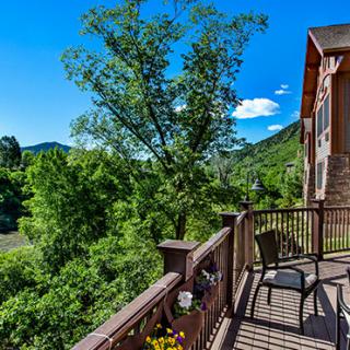 A scenic view from a balcony overlooking lush greenery and distant hills under a clear blue sky.