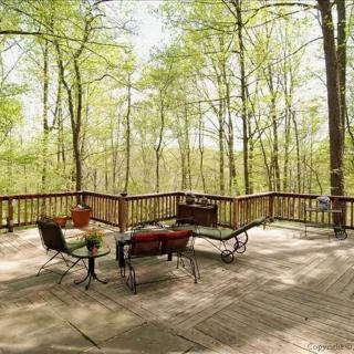 A spacious outdoor deck with comfortable seating and a scenic forest view.