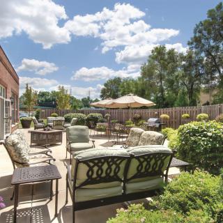 A spacious patio with comfortable outdoor seating and lush greenery on a sunny day.