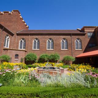 A beautifully landscaped garden in front of a brick building under a clear blue sky.