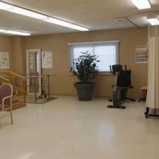 A physical therapy room with exercise equipment and seating area.