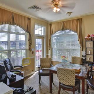 A cozy office space with a table, chairs, and large windows adorned with curtains.