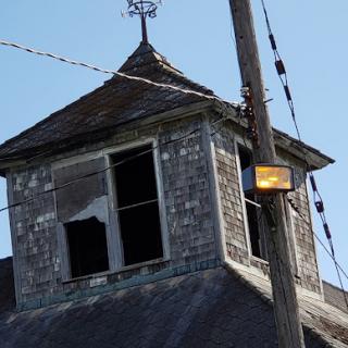 An abandoned building with broken windows and a weathered roof, showcasing the passage of time.