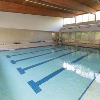 An empty indoor swimming pool with clear blue water and lanes marked.