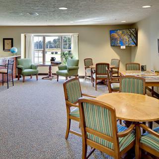 A spacious and well-lit seating area with chairs and tables, featuring large windows that let in natural light.
