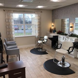 A well-lit hair salon with styling chairs and mirrors, featuring comfortable seating and modern decor.