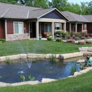 A view of a house with a landscaped garden and pond in the foreground.