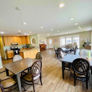 A spacious dining and kitchen area with multiple tables and chairs, illuminated by natural light.
