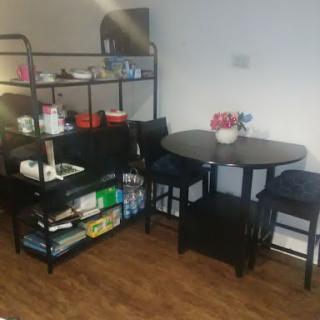 A cozy kitchen dining area featuring a round table, chairs, and shelves filled with various items.