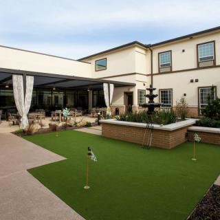 A well-maintained courtyard with a fountain, outdoor seating, and a manicured lawn.