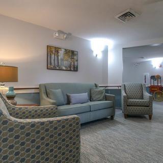 A cozy living room featuring a sofa, armchairs, a coffee table, and artwork on the wall.