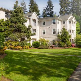 A well-maintained apartment building with lush green lawns and surrounding trees.