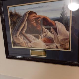 A framed painting depicting a contemplative figure wrapped in spiritual attire, set against a serene landscape.