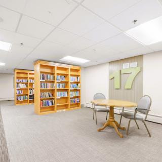 A quiet library space featuring wooden bookshelves, a table, and chairs perfect for studying.