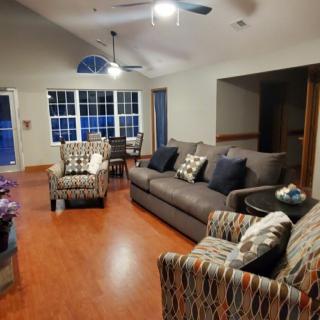 A cozy living room with a modern design, featuring a sofa and armchairs on a wooden floor.