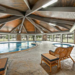 A spacious indoor pool area with wooden ceiling and lounge chairs.