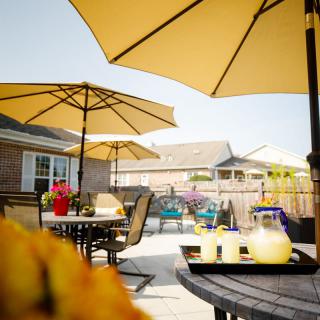 A sunny patio with umbrellas, tables, and chairs set for a relaxing outdoor gathering.
