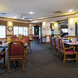 A cozy dining area with neatly arranged tables and chairs, featuring a warm interior decor.