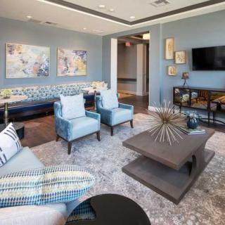 A modern living room with a blue color scheme, featuring comfortable seating, a stylish coffee table, and decorative artwork on the walls.