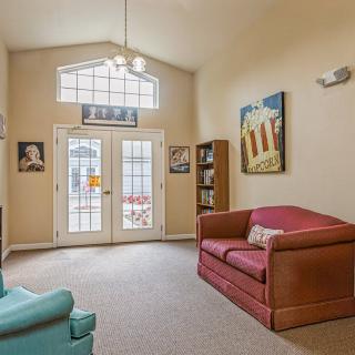 A cozy living room featuring comfortable sofas, artwork on the walls, and a bookshelf by the window.