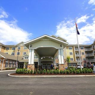 A residential building with a grand entrance and well-maintained landscaping under a clear blue sky.