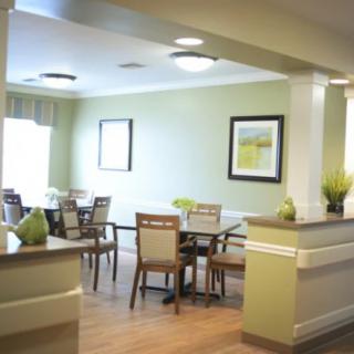A well-lit dining area with several tables and chairs, adorned with plants and wall artwork.