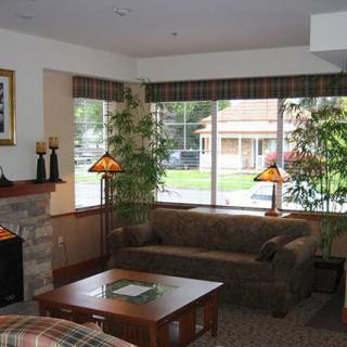 Cozy living room with a sofa, coffee table, fireplace, and large windows allowing natural light to enter.