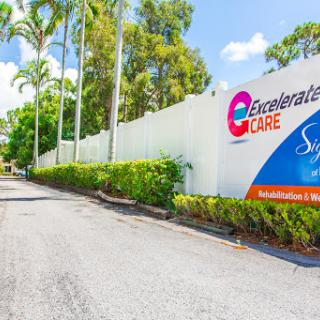Entrance to a healthcare facility surrounded by palm trees and greenery.