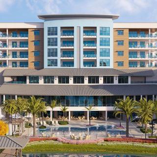 A luxurious hotel with a large swimming pool and palm trees in the foreground.
