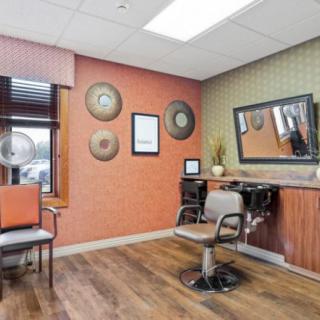 An inviting salon interior with a styling chair, mirror, and decorative wall accents.