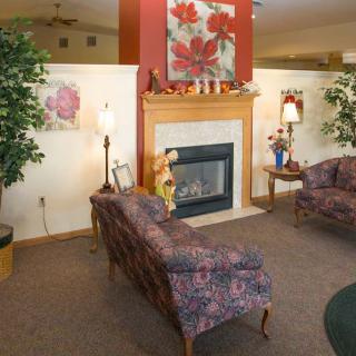 A cozy living room with a fireplace, surrounded by floral artwork and comfortable couches.