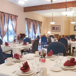 An elegantly set dining room with neatly arranged tables and chairs, featuring decorative napkins and tableware.