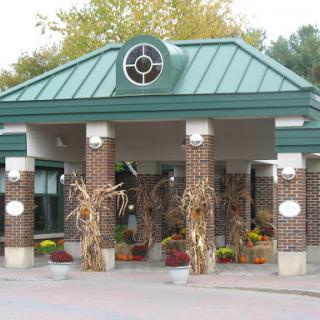 A charming entrance adorned with autumn decorations, featuring corn stalks and vibrant flowers.