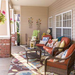 A cozy porch with wicker furniture, vibrant cushions, and decorative accents.