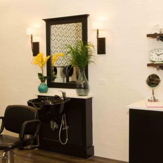 A well-decorated hair salon interior with a styling chair, sink, and mirror.