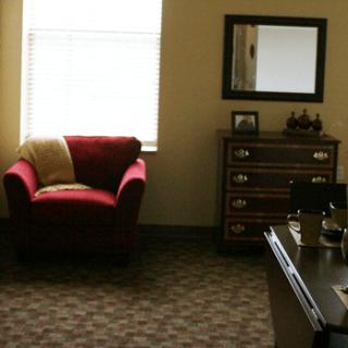 A cozy office space with a red chair and wooden furniture.