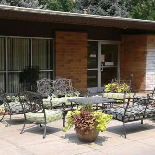 A cozy patio area with metal furniture and potted plants outside a brick building.