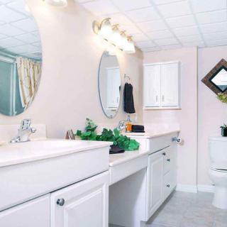 A modern bathroom with a large mirror, sink, and cabinets.