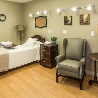 A cozy hospital room featuring a single bed, a comfortable chair, and decorative elements to create a welcoming atmosphere.