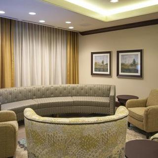 A modern waiting room with a curved sofa, comfortable chairs, and framed artwork on the walls.