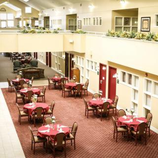 An indoor dining area with multiple tables and chairs arranged on a carpeted floor.