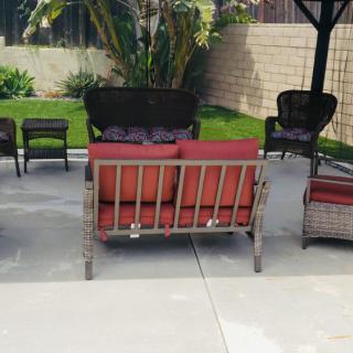 Outdoor patio set with cushioned chairs and sofa in a garden setting.