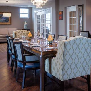 Elegant dining room with a large table and plush chairs under a chandelier.
