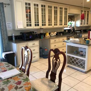 A spacious kitchen with white cabinets, wooden chairs, and a central island.