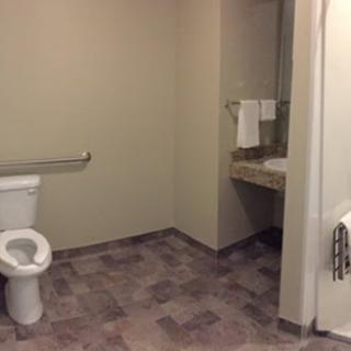 A view of a simple bathroom with a toilet, sink, and accessible features.