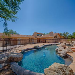 A serene backyard with a swimming pool surrounded by rocks and trees on a sunny day.
