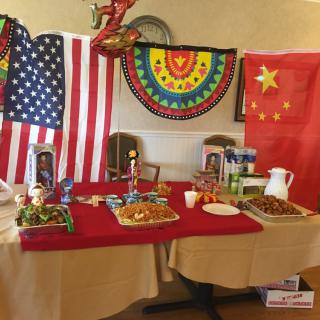 A table adorned with American and Chinese flags, featuring a variety of foods, set up for a cultural event.